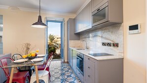A kitchen with a marble countertop, a built-in oven, and a dining area with a table set for two. - Luxury 2BR Valletta Apartment - Square Sea View (Valletta)