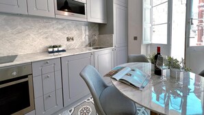 A modern kitchen with grey cabinets, a built-in oven, and a window with a view of the street. - Local Living 2BR 2BA With Patio - Duplex Apartment (Valletta)