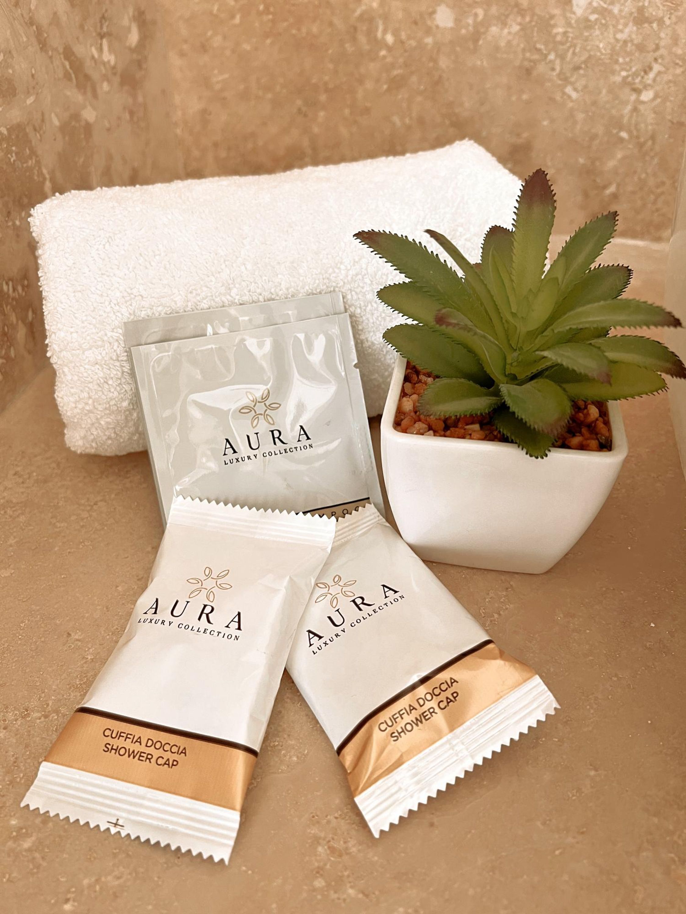 Een set luxe douchemutsen, een potplant en een witte handdoek.