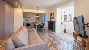 Un salon comprenant un canapé, une table à manger avec des chaises, une cheminée et un téléviseur.