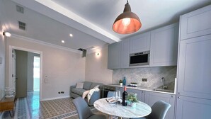Une cuisine moderne avec des meubles gris, un four encastré et un plan de travail en marbre.