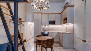A modern kitchen with a dining area, featuring a chandelier, a stove, and a sink. - Modern Luxury Studio Apartment (Sliema)