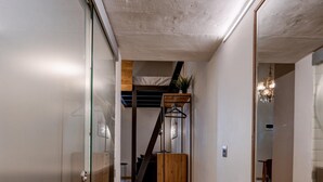 A hallway with stone flooring, a wooden staircase, and a mirrored wall. - Modern Luxury Studio Apartment (Sliema)