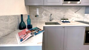A modern kitchen with grey cabinets, a stainless steel sink, and a built-in oven. - Local Gem Spacious 2BR 2BA Duplex Apartment (Valletta)