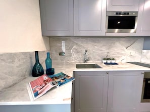 A modern kitchen with grey cabinets, a stainless steel sink, and a built-in oven. - Local Gem Spacious 2BR 2BA Duplex Apartment (Valletta)