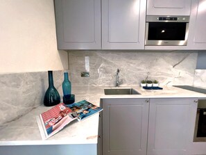 A modern kitchen with grey cabinets, a stainless steel sink, and a built-in oven. - Local Gem Spacious 2BR 2BA Duplex Apartment (Valletta)