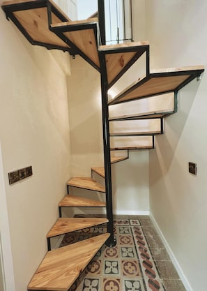 A spiral staircase with wooden steps and black metal railings. - Local Gem Spacious 2BR 2BA Duplex Apartment (Valletta)