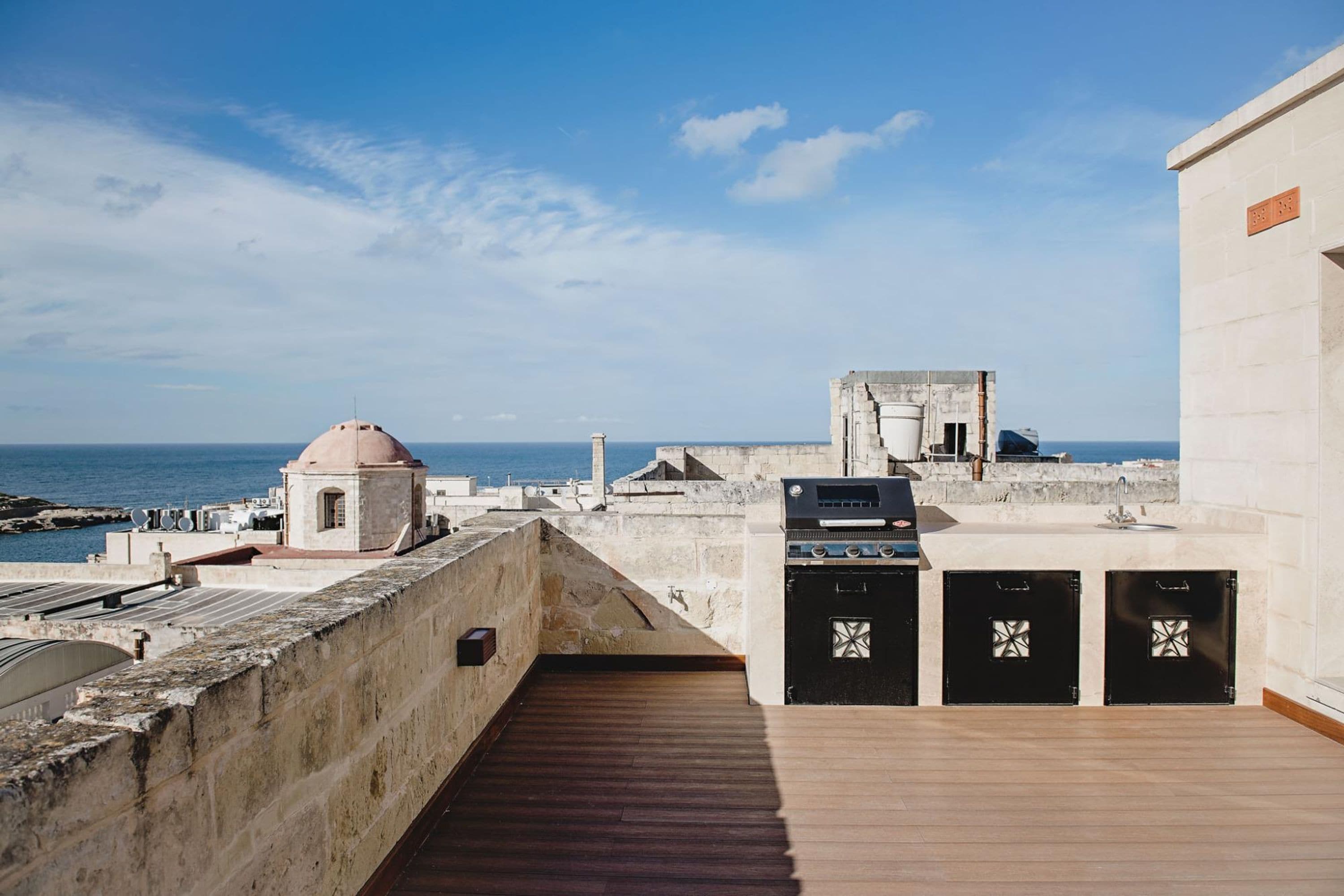 A rooftop terrace with a view of the sea, a small dome structure, and a grill area.