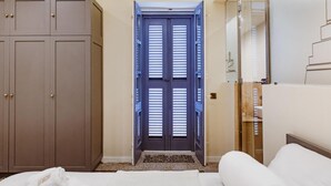 A bedroom with a bed, a wardrobe, and a bathroom with a mirror. - Sea View Penthouse - Duplex (Valletta)