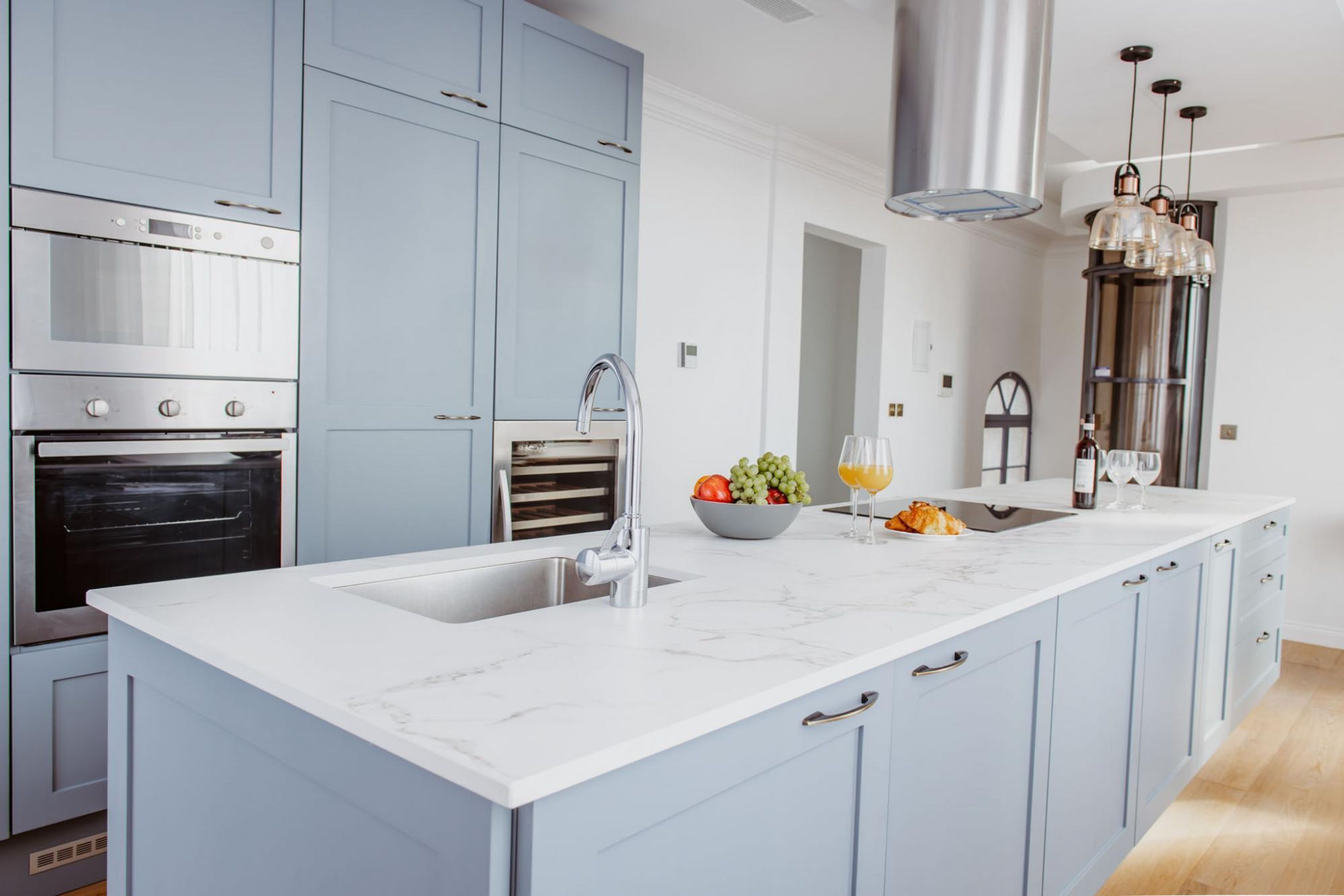 A modern kitchen with a large island, stainless steel appliances, and light blue cabinetry.