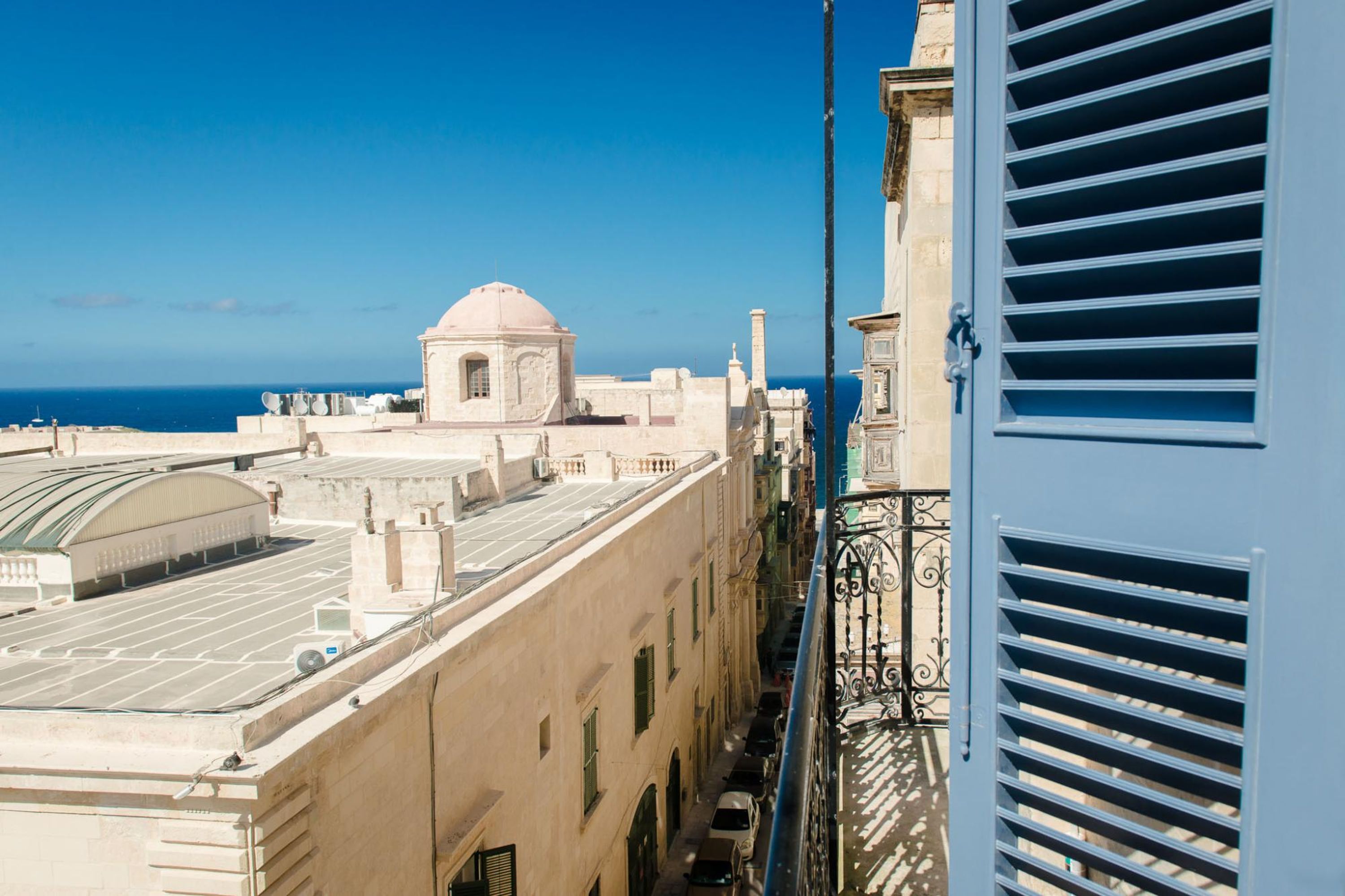 A building with a dome, a balcony with metal railings, and a view of the sea.