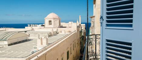 A building with a dome, a balcony with metal railings, and a view of the sea.