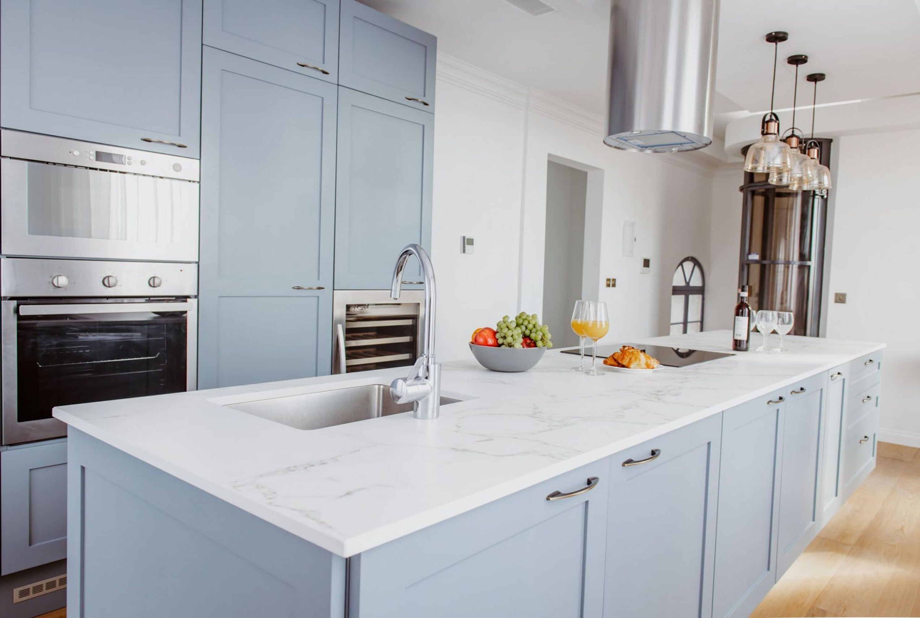 Une cuisine moderne dotée d’un grand îlot central, d’appareils électroménagers en acier inoxydable et de meubles de couleur bleu clair.