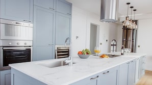 A modern kitchen with a large island, stainless steel appliances, and light blue cabinetry. - Sea View Penthouse - Duplex (Valletta)