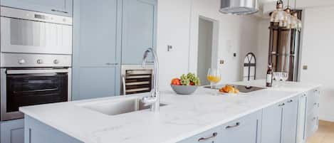 Une cuisine moderne dotée d’un grand îlot central, d’appareils électroménagers en acier inoxydable et de meubles de couleur bleu clair.
