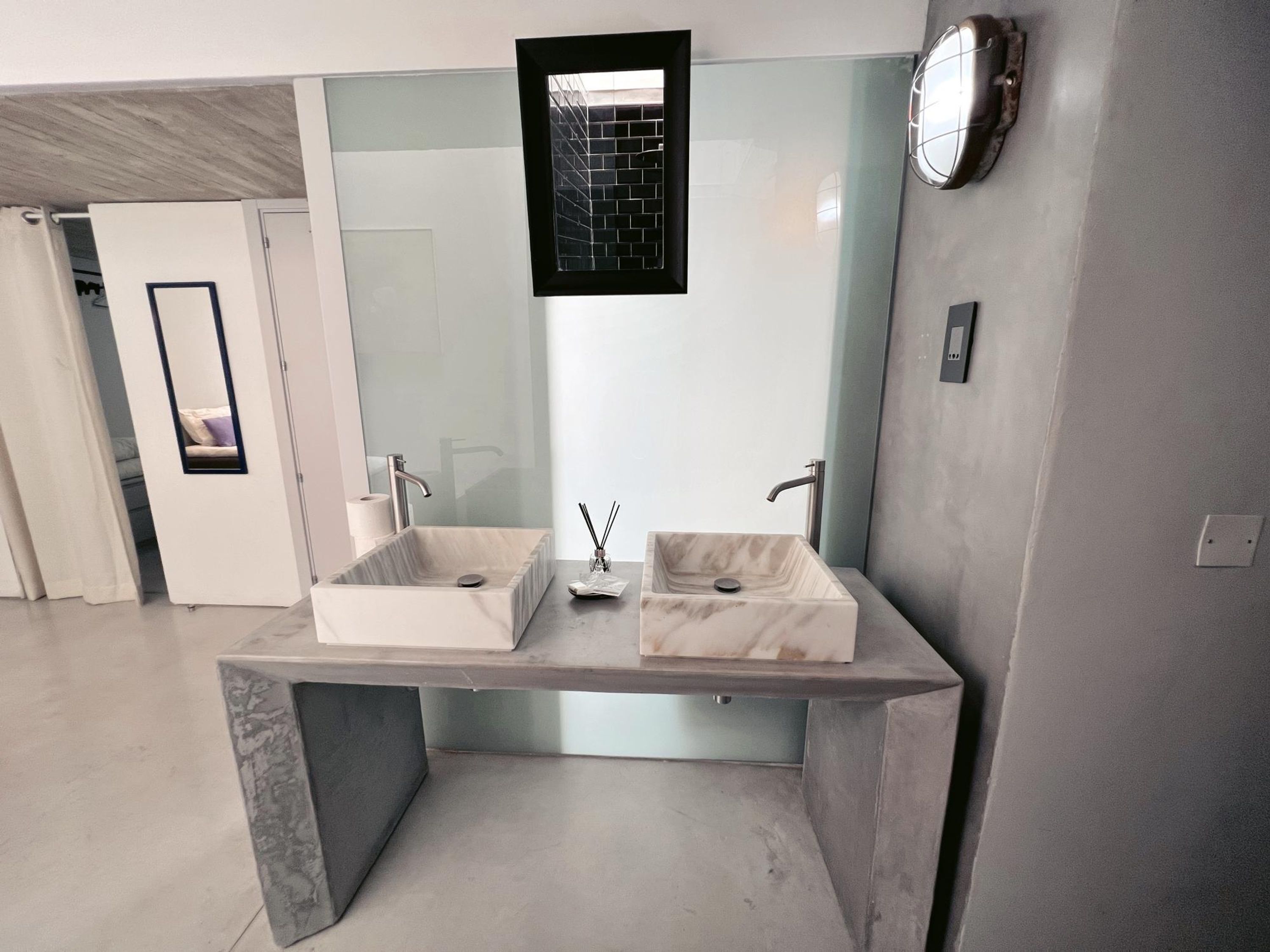 A modern bathroom with two marble sinks, a glass shower enclosure, and a large mirror.