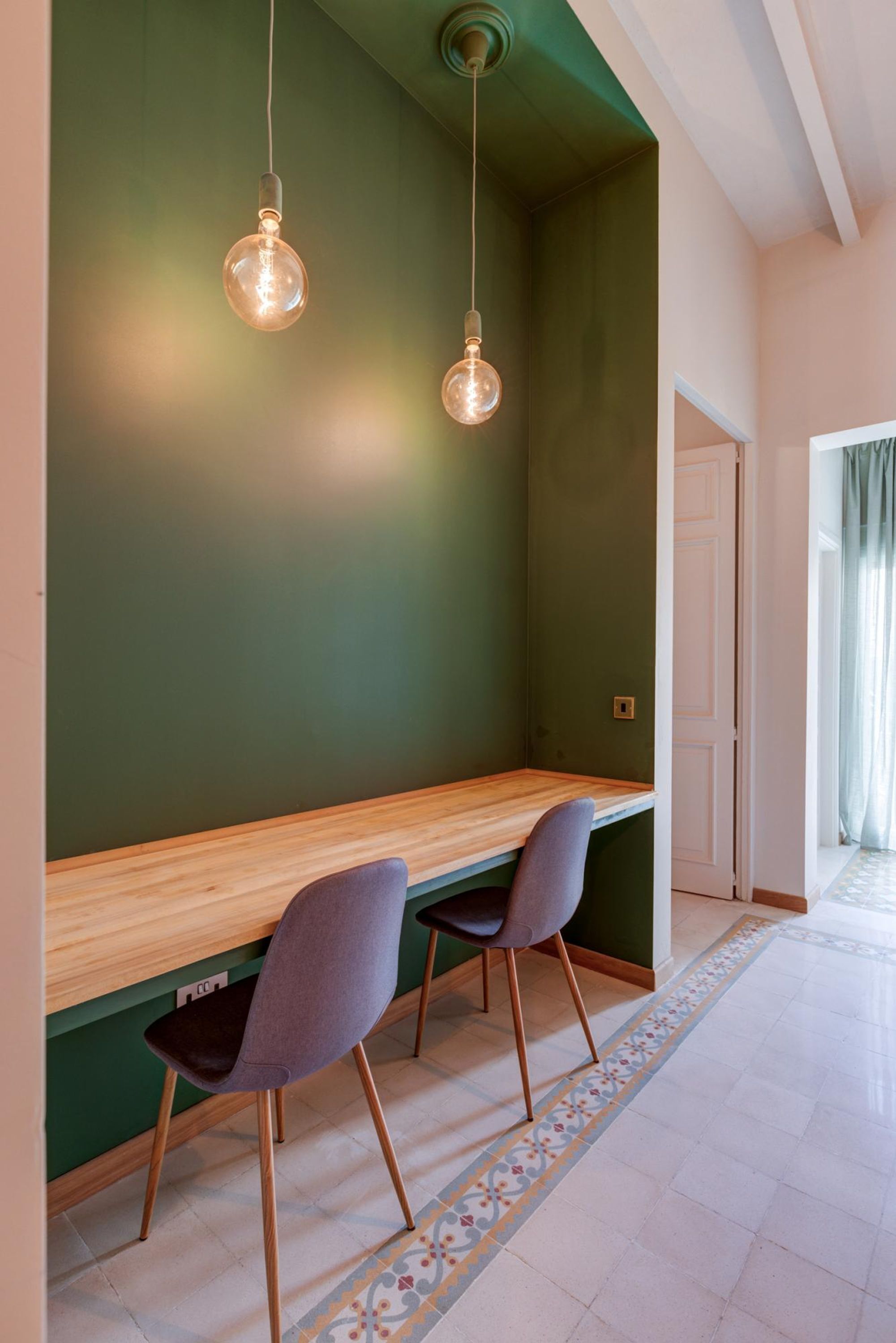 Une pièce avec un banc en bois, deux chaises et des ampoules suspendues au plafond.