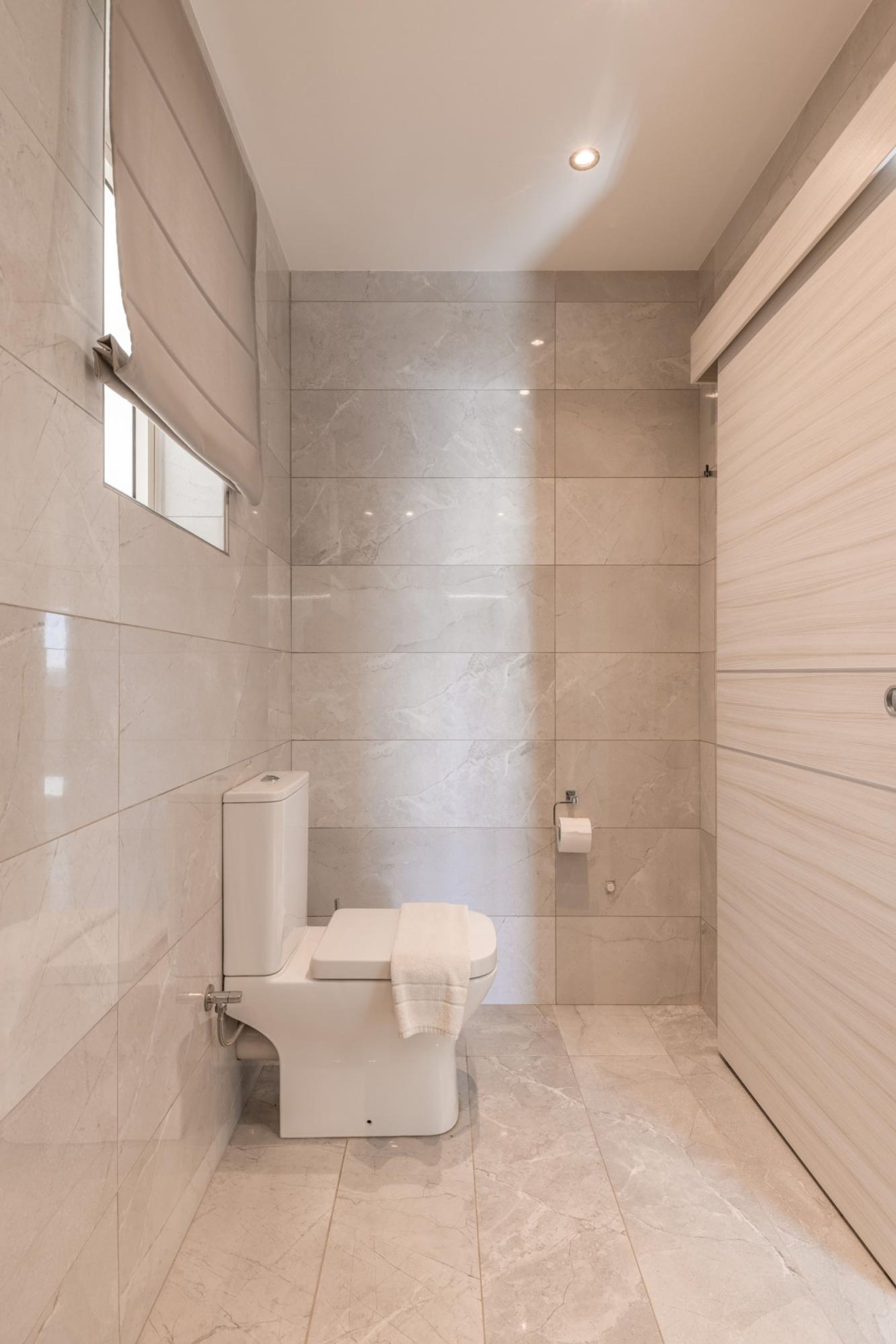 Ein modernes Badezimmer mit Toilette, Handtuchhalter und einem Händetrockner.