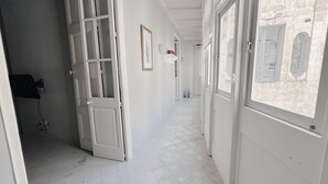 Un pasillo con puertas y ventanas blancas que da a una habitación con vistas a un edificio.