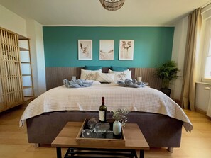 Un dormitorio con cama, una mesita de noche con una botella y un vaso, y una bandeja con un florero.