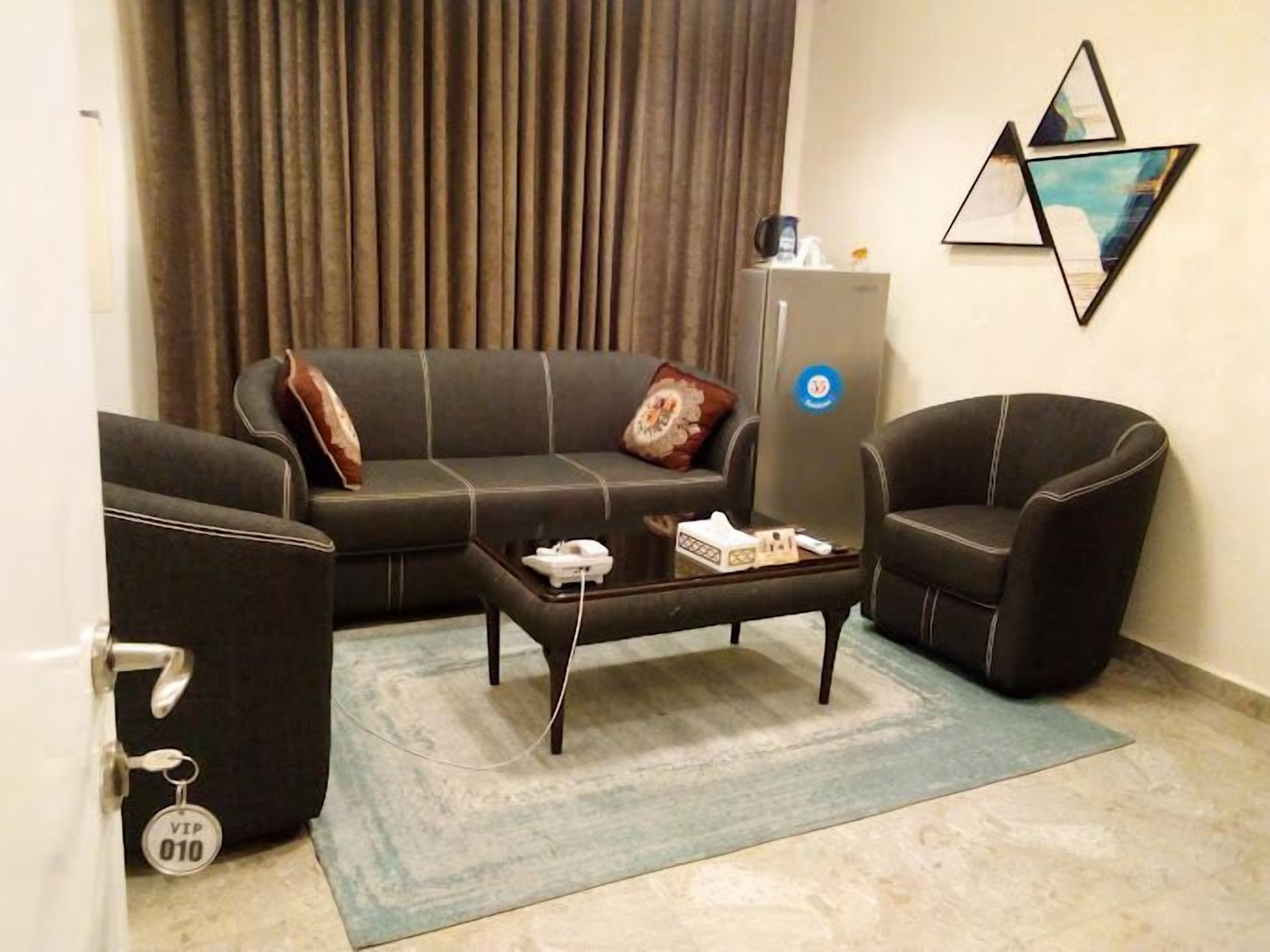 A modern living room with a sofa, armchairs, a coffee table, and a minibar.