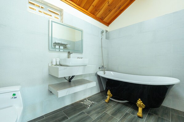 A modern bathroom with a freestanding bathtub, a vanity with a mirror, and a toilet. - Herbal Resort (Phu Quoc)
