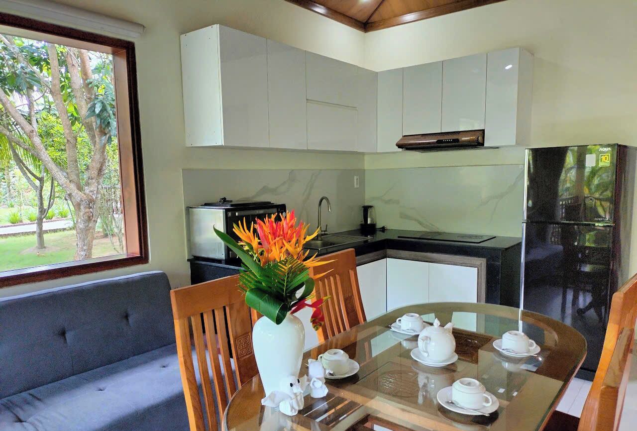 A modern kitchen with white cabinets, a black refrigerator, and a dining area with a glass table and chairs.