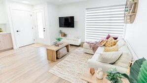 A modern living room with a sofa, coffee table, and a TV mounted on the wall. - *Refresh | Central & Trendy | 5 min to downtown* (Winnipeg)