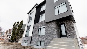 A modern multi-story residential building with a mix of brick and stucco exterior, large windows, and a visible entrance with steps. - *Refresh | Central & Trendy | 5 min to downtown* (Winnipeg)