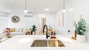 A modern kitchen with a central island, stainless steel sink, and pendant lighting. - *Refresh | Central & Trendy | 5 min to downtown* (Winnipeg)