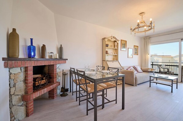 A living room with a fireplace, dining table, and a balcony with a view.