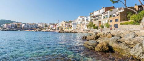 A coastal town with colorful buildings, clear water, and rocky shoreline.