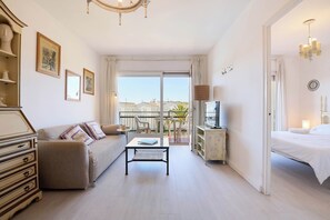 Relax in this stylish room with a comfortable sofa, armchair, and neatly made bed, plus a balcony with a table and chairs.