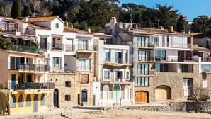Une rangée d’immeubles à étages, dotés de balcons et de façades en pierre, avec une colline en arrière-plan.