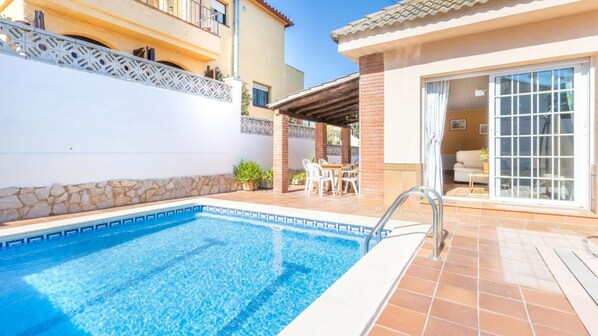 A swimming pool with a tiled deck, a covered patio area, and a building with a balcony. - Del Pi in Blanes With 4 Bedrooms and 3 Bathrooms (Blanes)