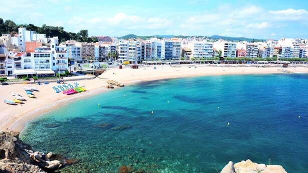 Una località balneare con una spiaggia sabbiosa, acque cristalline e ombrelloni colorati.