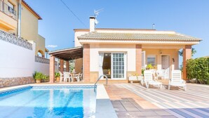 Una casa a due piani con piscina, area salotto esterna e patio coperto.