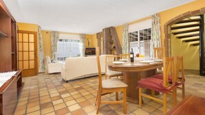 Una stanza con tavolo da pranzo, sedie, divano e televisore.