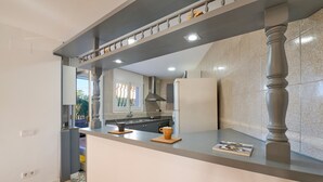 Une cuisine moderne avec un plan de travail gris, une cuisinière encastrée et une grande fenêtre.
