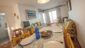 Un coin repas avec une table dressée pour quatre personnes, un téléviseur et un tableau accroché au mur.