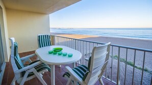 Un balcon avec une table ronde et des chaises, donnant sur une plage.