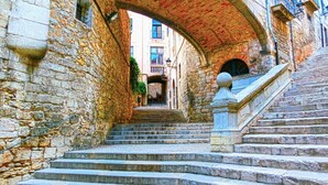 Un escalier en pierre mène à un bâtiment surmonté d’une arche en briques.