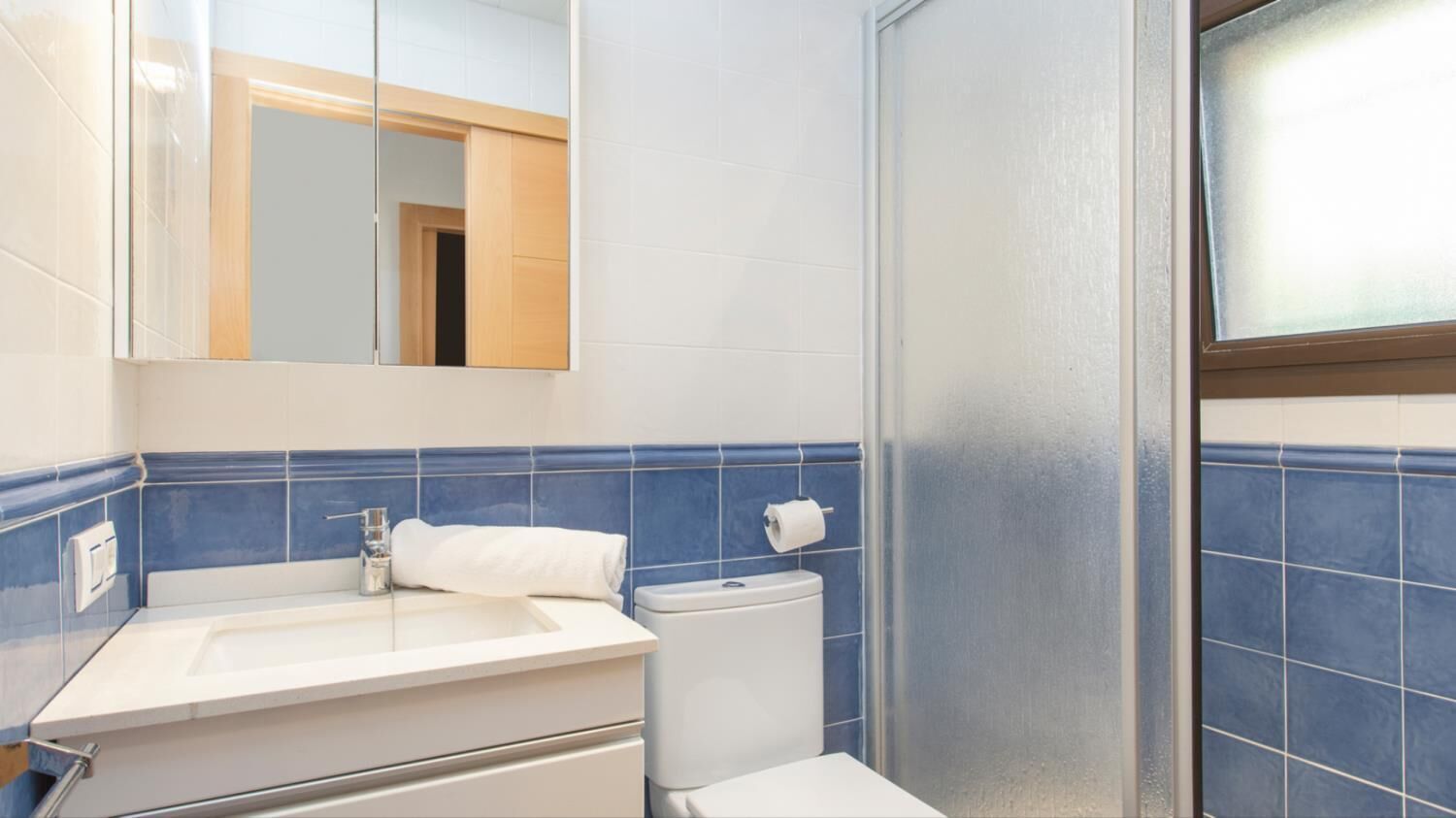 A bathroom with a white sink, a toilet, and a glass shower enclosure.