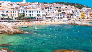 A coastal town with white buildings, a sandy beach, and clear blue water. - Canadell 1 in Calella de Palafrugell (Palafrugell)