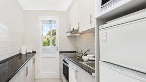 A compact kitchen with white cabinetry, a black countertop, a built-in oven, and a dishwasher. - Canadell 1 in Calella de Palafrugell (Palafrugell)
