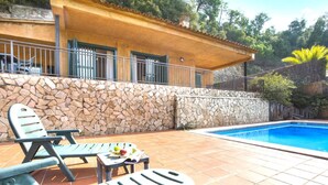 A poolside area with lounge chairs and a stone wall.