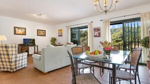 A dining area with a glass table, wicker chairs, and a sofa.