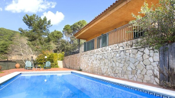 A swimming pool with a stone wall and a wooden deck.