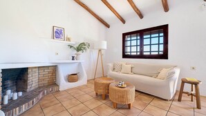 A living room with a fireplace, a sofa, two wicker ottomans, and a window. - Serena in Lloret de Mar (Lloret de Mar)