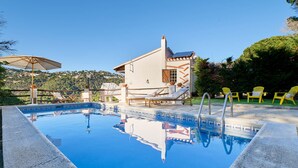 A swimming pool with lounge chairs and umbrellas, surrounded by a house with a tiled roof and a view of the hills. - Serena in Lloret de Mar (Lloret de Mar)